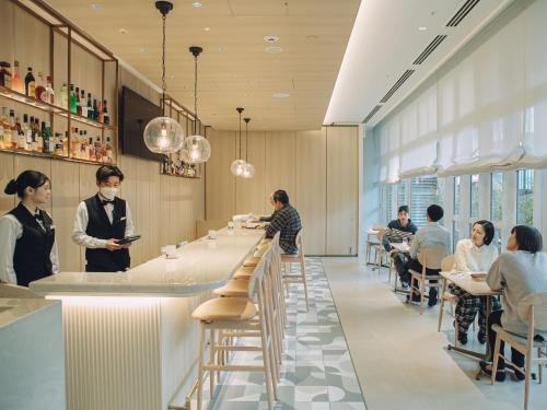 Un restaurante con gente sentada en mesas y un bar. en Wishton Hotel Yukari, en Sakura