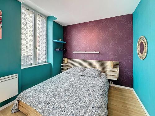 Un dormitorio con una cama y una pared morada. en T2 Almarc, en Châtel-Guyon