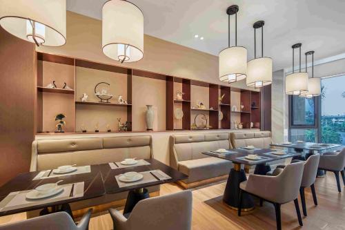 a dining room with tables and chairs and chandeliers at 西双版纳熙源国际酒店 in Jinghong