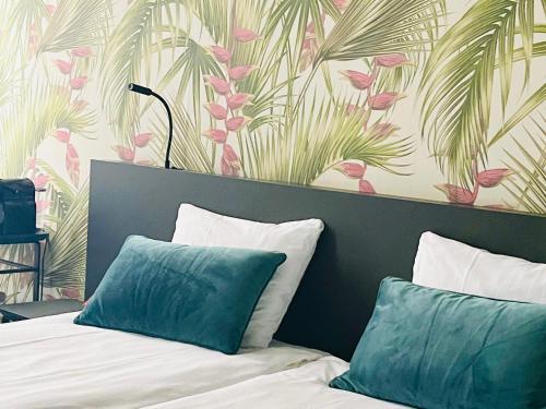 Una cama con dos almohadas y una pared con hojas de palma. en Hotel Sutor, en Breda