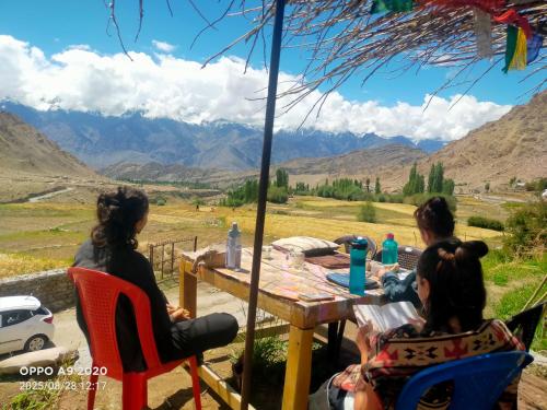 three women sitting at a table with a view of mountains at Old Likir Traditional Farm Stay in Leh
