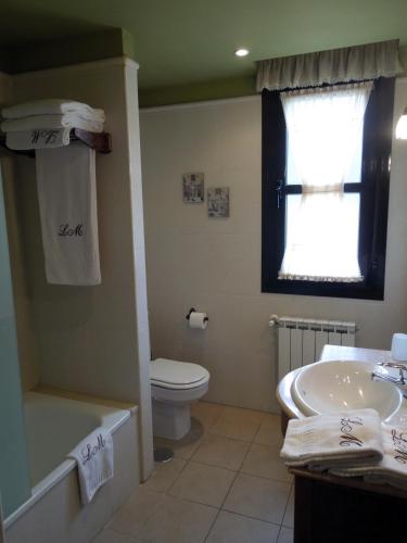 a bathroom with a sink and a toilet and a window at Apartamentos la Marina in Ribadesella