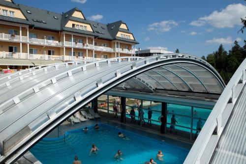 un groupe de personnes se baignant dans une piscine sous un pont dans l'établissement Grand Hotel Strand, à Vyšné Ružbachy