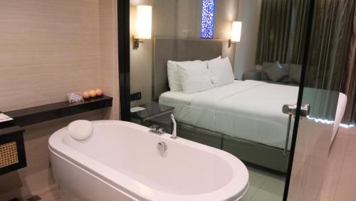 a bathroom with a sink and a bed and a tub at THE TJ HOTEL Pattaya in Jomtien Beach