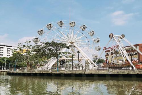 a ferris wheel in a park next to a river at Sleepy Nomad Hostel in Melaka