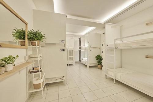a room with white bunk beds and potted plants at Sleepy Nomad Hostel in Melaka