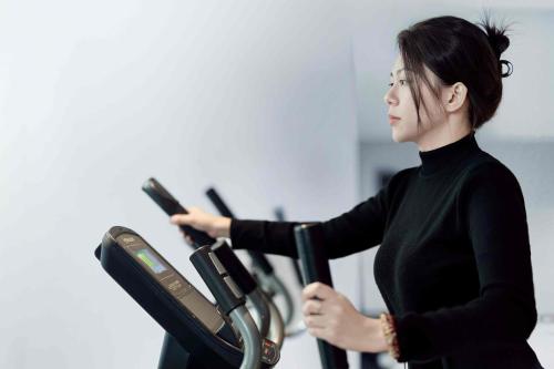 a woman in a gym holding a machine at 西双版纳熙源国际酒店 in Jinghong