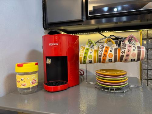 a kitchen counter with a red coffee maker and plates at Unique Vibes Staycation in Punta