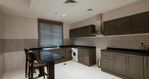 a kitchen with brown cabinets and a washer and dryer at Baithans 24 Furnished Apartments Hotel LLC in Ajman 