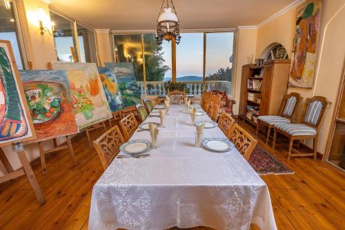 a dining room with a long table with chairs and paintings at Ha'Seuda Ha'Achrona Suites in Amirim