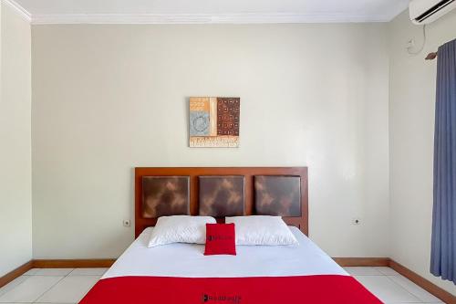 a bedroom with a large bed with a red blanket at RedDoorz near Exit Toll Kalijati Subang in Pagon