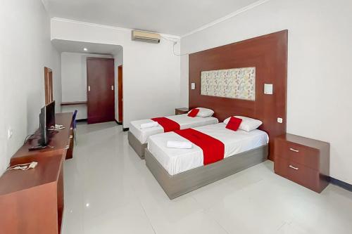 a bedroom with two beds and a flat screen tv at RedDoorz near Exit Toll Kalijati Subang in Pagon