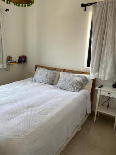 a bedroom with a bed with white sheets and a window at Tirza's Place in Livnim