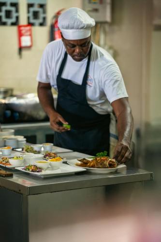 a chef preparing plates of food in a kitchen at Beach House Beau Vallon in Beau Vallon