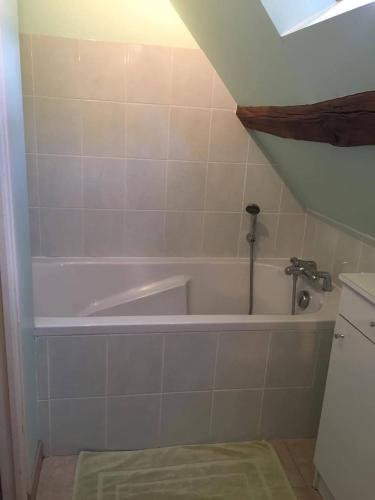 a bathroom with a white bath tub in a room at Le Côtier in Margon