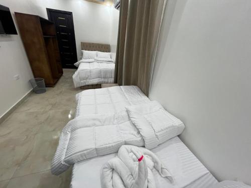 three beds in a room with white sheets and towels at Aladdin Sphinx & Pyramid Stay in Cairo