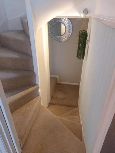 a hallway with stairs with a mirror and a circular mirror at Clifftop Mews - Westcliff - Ramsgate - Pet friendly! in Kent