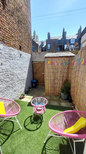 a patio with two chairs and a table on the grass at Clifftop Mews - Westcliff - Ramsgate - Pet friendly! in Kent