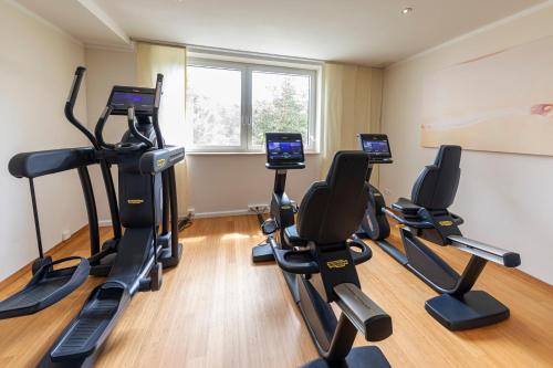 a gym with tread machines in a room with a window at Strandhotel Dünenmeer - Adults only in Dierhagen