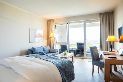 a hotel room with a bed and a desk and a desk at Strandhotel Dünenmeer - Adults only in Dierhagen