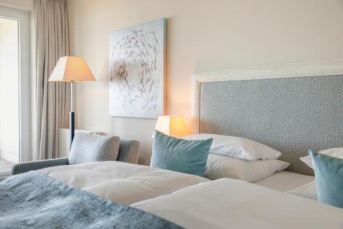 a hotel room with two beds and a chair at Strandhotel Dünenmeer - Adults only in Dierhagen