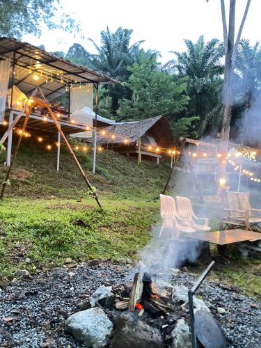 a campfire with two chairs and a picnic table at Amornkeeree Khao Sok Camping in Khao Sok
