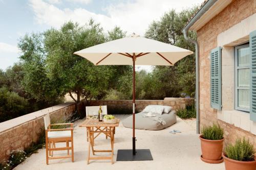 a patio with a table and an umbrella at Predi Son Jaumell Hotel Rural in Capdepera