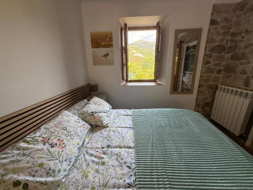 a bedroom with a bed with a comforter and a window at Casa del Tesoro II in Cangas de Onís