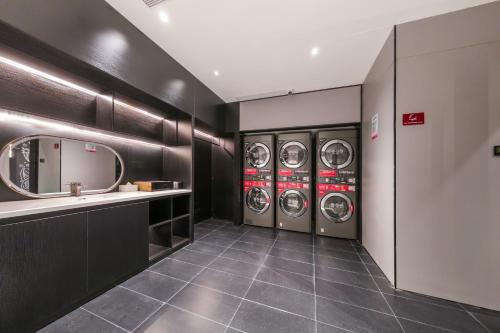 a laundry room with three washing machines and a sink at Ibis Huangshan Scenic Area Hotel in Huangshan Scenic Area