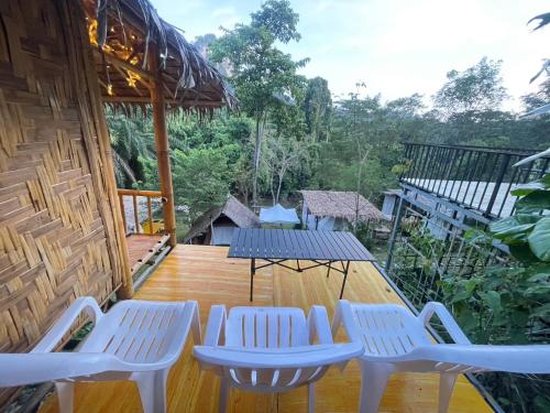 a deck with white chairs and a table at Amornkeeree Khao Sok Camping in Khao Sok