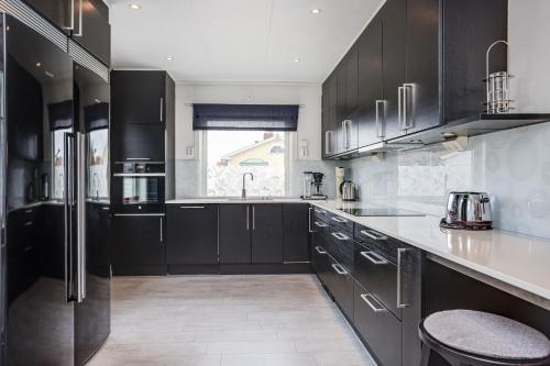 a kitchen with black cabinets and a sink at Cozy House near Beach, City & Activities in Falkenberg