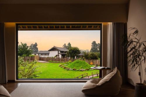 a room with a large window with a view of a yard at LiJiang Mountain Spring Resort in Baisha