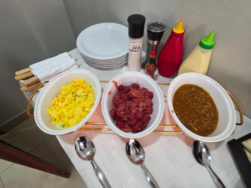 three bowls of food sitting on a table with spoons at White Garden Hotel in Maputo