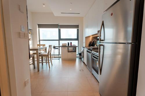 a kitchen with a stainless steel refrigerator and a table at Enjoy Scenic 1BR with BeachAccess Parking at Pixel504 in Abu Dhabi