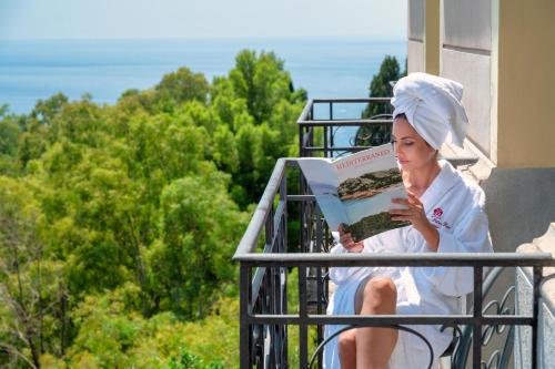 a woman sitting on a balcony reading a book at Excelsior Palace Hotel in Taormina