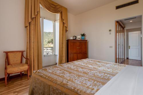 a bedroom with a bed and a window and a chair at Excelsior Palace Hotel in Taormina