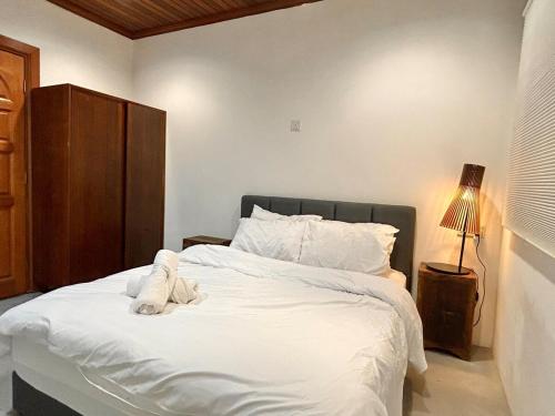 a bedroom with a bed with white sheets and a lamp at Chic Designer Bedroom in Shared Bungalow near LRT SS1 PJ in Petaling Jaya