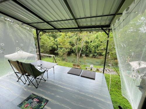 a patio with a table and chairs and a view of a lake at Amornkeeree Khao Sok Camping in Khao Sok