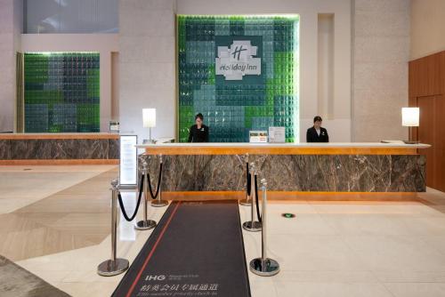 a lobby with a bar with two people standing behind it at Holiday Inn Shanghai Pudong Kangqiao by IHG - Free shuttle bus to Disney land, Ins Swimming Pool in Shanghai
