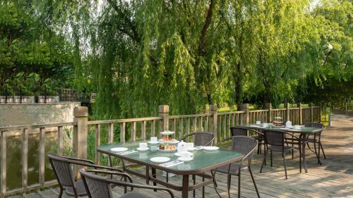 two tables and chairs on a deck with a fence at Holiday Inn Shanghai Pudong Kangqiao by IHG - Free shuttle bus to Disney land, Ins Swimming Pool in Shanghai