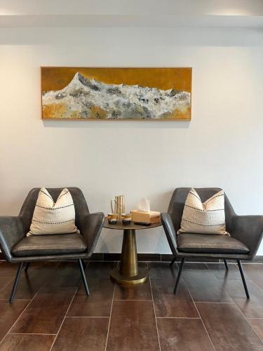 two chairs and a table with a painting on the wall at Appartementhaus AURUM - Summercard included in Zell am See