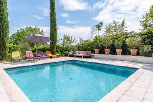 a swimming pool with chairs and an umbrella at Les Vignes - Newly refurbished 18th century house with Mediterranean garden in Caluire-et-Cuire