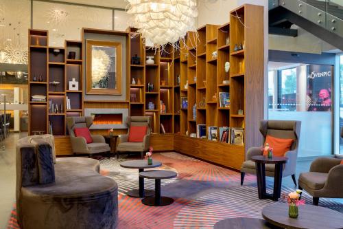 a library with chairs and tables and bookshelves at Mövenpick Hotel Amsterdam City Centre in Amsterdam