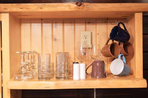 a shelf with glasses and wine glasses on it at Little Redwood - Hocking Hills, Hot Tub & Games in Logan
