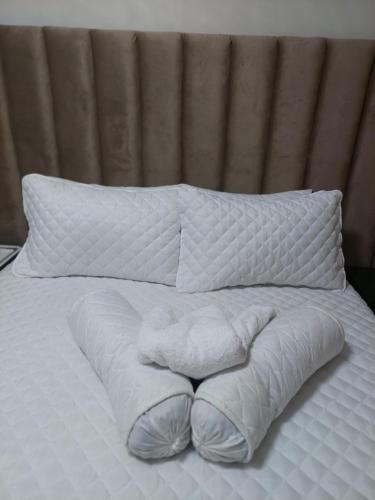 a bed with white blankets and pillows on it at A call for all guests in Pretoria