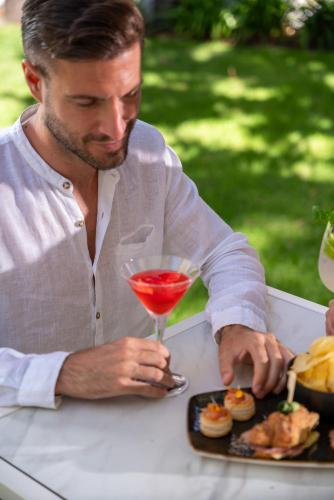 a man sitting at a table with a drink and a plate of food at Bolina Suite & Spa in Milano Marittima