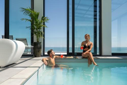 a man and a woman sitting in a swimming pool at Bolina Suite & Spa in Milano Marittima