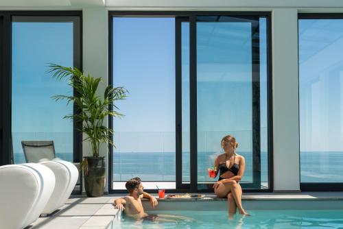 a woman sitting in a swimming pool with a child at Bolina Suite & Spa in Milano Marittima