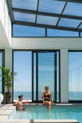 a man and a woman sitting in a swimming pool at Bolina Suite & Spa in Milano Marittima