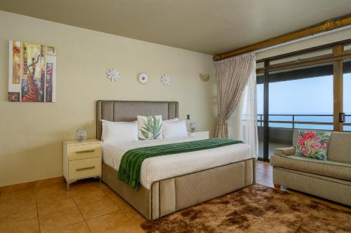 a bedroom with a bed and a chair and a window at Ya Rona Sea View -5 Bedroom Ramsgate Holiday Home KRB1 in Margate